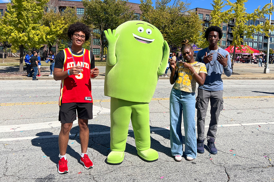 Three Georgia State University students posing outdoors with the Cricket Wireless mascot Chip during a campus event