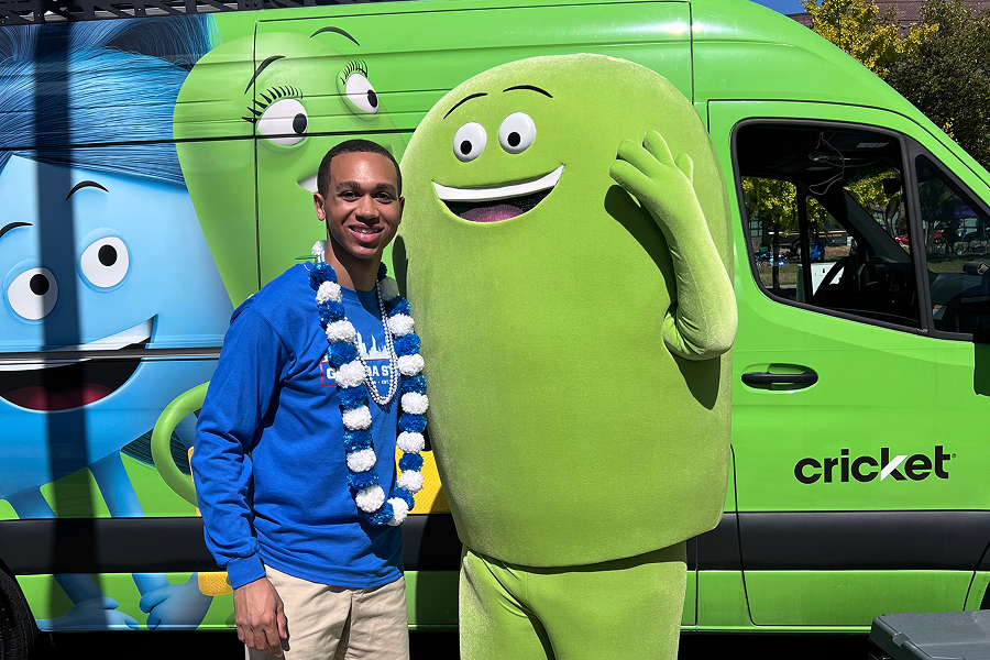 Georgia State University student in Panthers gear posing with Cricket Wireless mascot Chip in front of a Cricket-branded van at a campus event