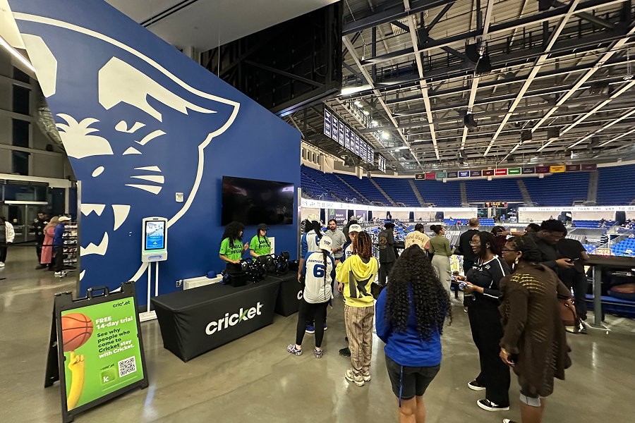Students and fans visiting the Cricket Wireless brand activation booth inside Georgia State University's arena, featuring the GSU Panther logo wall