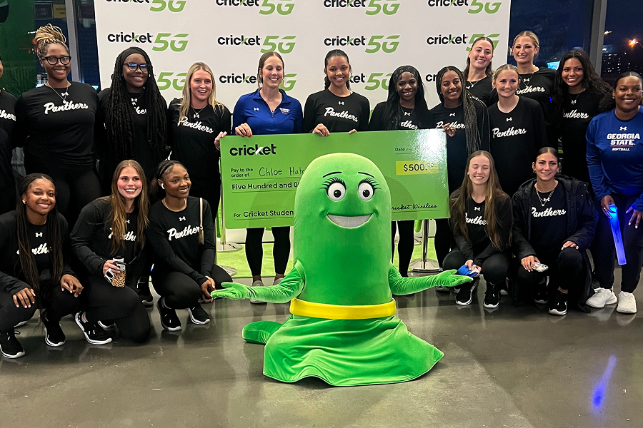 Georgia State University Panthers softball team posing with the Cricket Wireless mascot and a $500 Cricket Student scholarship check in front of a Cricket 5G backdrop