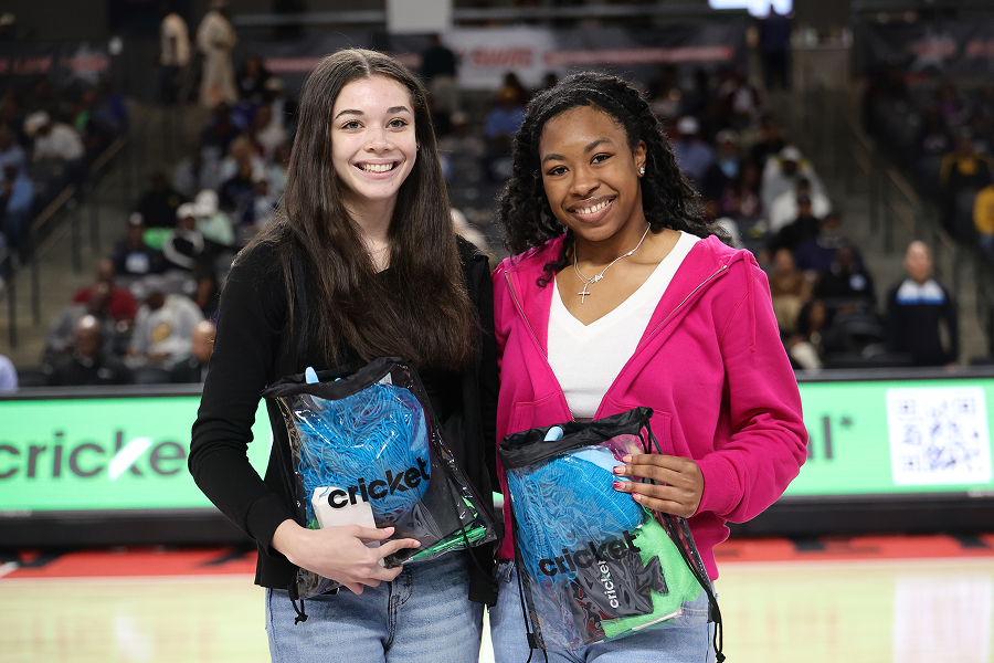 Two young fans holding Cricket Wireless branded prize bags courtside at a SWAC Basketball Tournament game