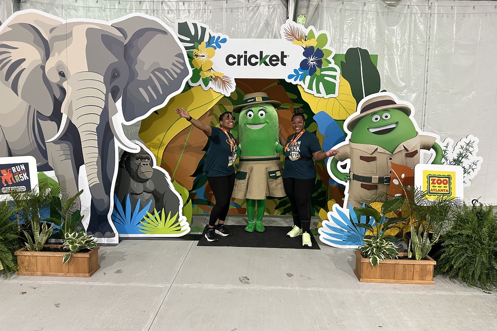 Runners posing with Cricket character Rose at the Cricket photo booth at the 2026 Run Like Wild 5K