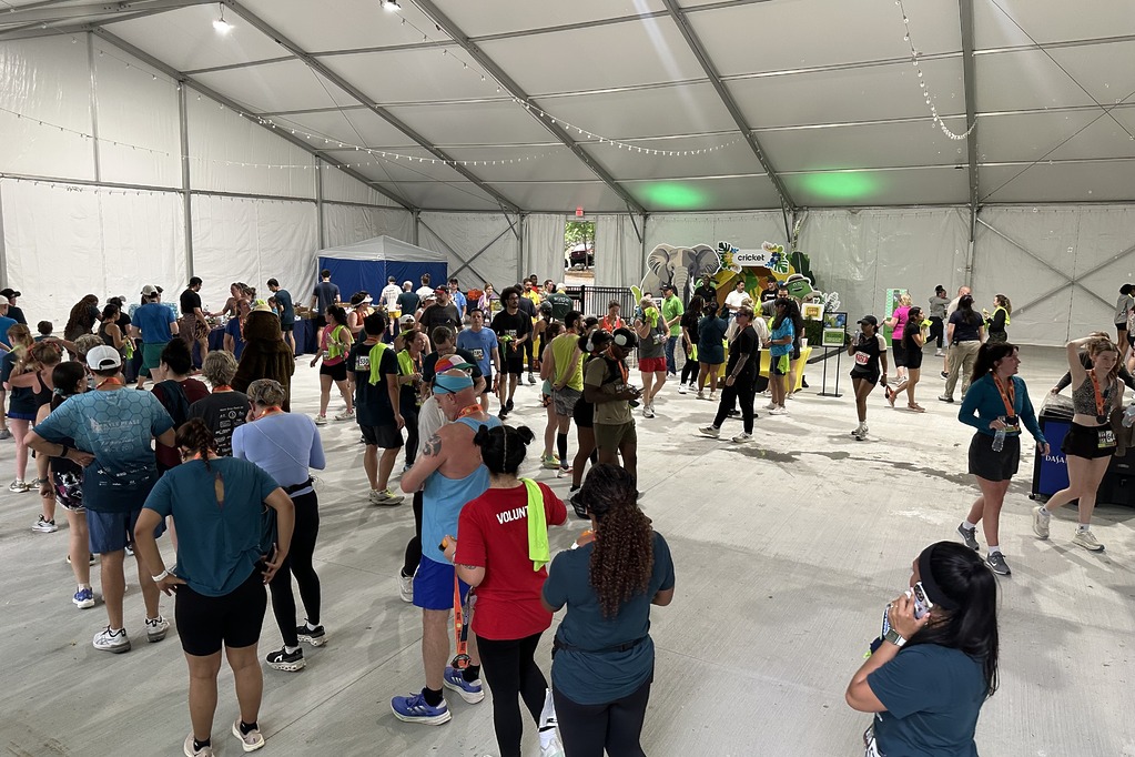 Crowd of runners celebrating in the Cricket tent at the 2026 Run Like Wild 5K at Zoo Atlanta