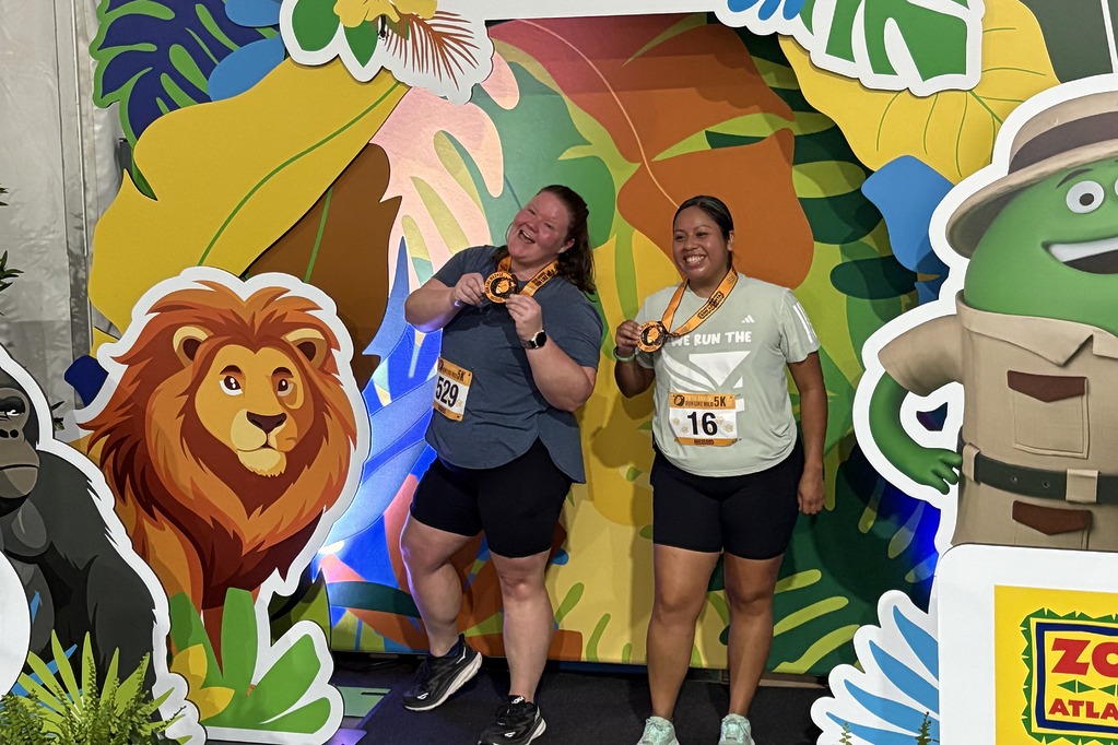 Two runners showing their bibs and medals at the Cricket photo booth at the 2025 Run Like Wild 5K