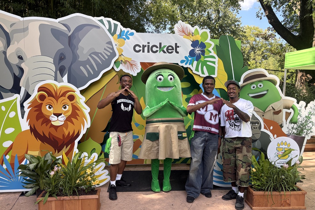 Young guests posing with Cricket character Rose in front of the lion and elephant photo backdrop at U at the Zoo