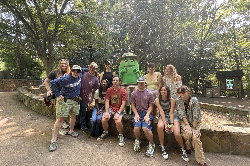 Group of guests gathered with a Cricket character beside an animal exhibit at Zoo Atlanta during U at the Zoo
